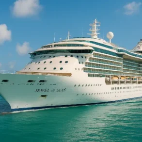 The cruise ship "Jewel of the Seas" glides through turquoise waters under a bright blue sky, showcasing its modern design.