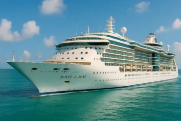 The cruise ship "Jewel of the Seas" glides through turquoise waters under a bright blue sky, showcasing its modern design.