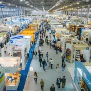 Aerial view of a busy trade exhibition hall filled with colorful booths and crowds of attendees exploring various displays.