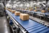 Industrial warehouse with rows of conveyor belts moving brown cardboard boxes. The setting is bright, spacious, and efficient, conveying automation.