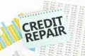 A notepad with "CREDIT REPAIR" written in bold on top of financial charts and spreadsheets showing various dollar amounts.