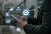 A person in a suit uses a smartphone, surrounded by glowing digital icons related to supply chain management, like gears and delivery trucks, symbolizing efficiency.
