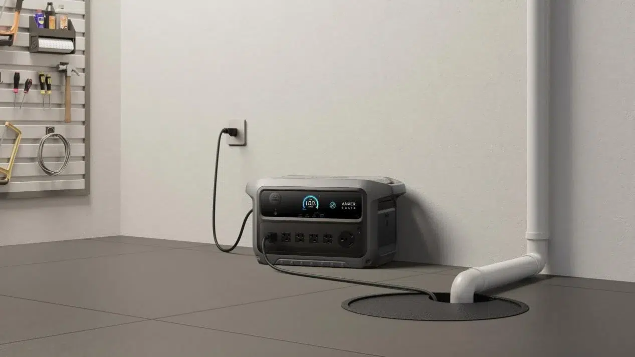 A portable generator in a garage is plugged into a wall socket, with a nearby sump pump. Tools are organized on a wall-mounted pegboard. The tone is utilitarian.