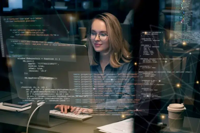 A woman with glasses smiles while working on a computer in a dimly lit office. Code and digital graphics are overlaid, conveying a tech-focused atmosphere.