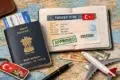 A map with an Indian passport, a Turkish keychain, a flight ticket, currency, and an open passport displaying an approved Turkey visa, alongside a toy airplane.