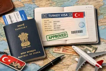 A map with an Indian passport, a Turkish keychain, a flight ticket, currency, and an open passport displaying an approved Turkey visa, alongside a toy airplane.
