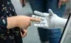 A child reaching out to touch a robotic hand, highlighting human-robot interaction in a modern setting.
