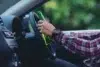 A person in a plaid shirt holds a green bottle while steering a car, suggesting the risky behavior of drinking and driving. The mood is tense.