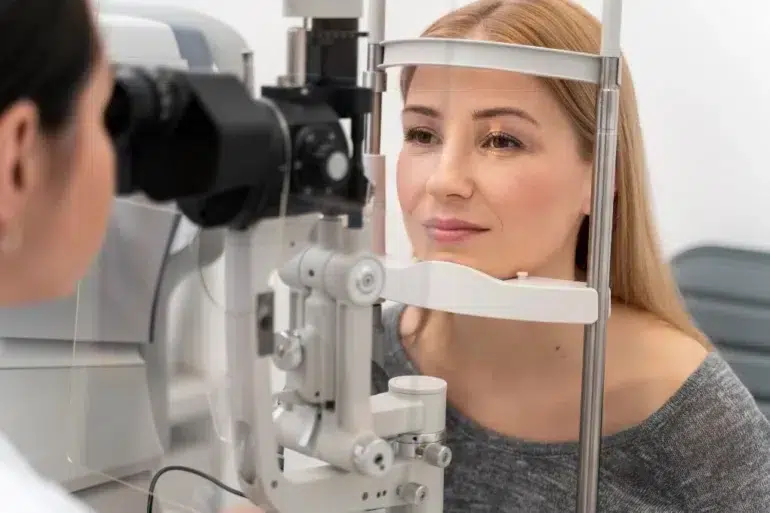 A patient undergoing an eye examination at an optical clinic, positioned in front of a slit lamp machine.