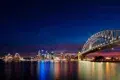 Sydney Harbour at night with the Harbour Bridge and Opera House illuminated against the city skyline
