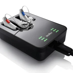 Charging dock with two hearing aids, one with a red and the other with a blue indicator, connected via USB cable.