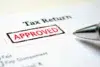 Close-up of a tax return document with a red "Approved" stamp. A pen lies nearby, conveying a sense of completion and approval.