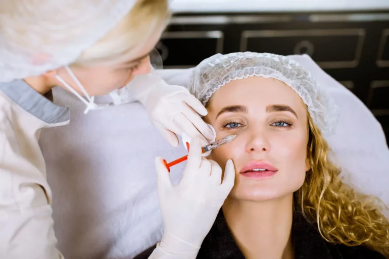 A medical professional administers a treatment using a syringe on a client in a clinical setting.