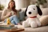 Snoopy Stuffed Animal plush sitting on a cozy bed with pillows