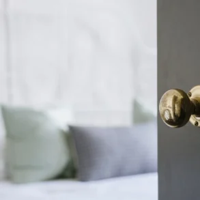 A close-up of a classic brass door knob on a dark wooden door, highlighting the elegance and timeless appeal of wooden door handles in home interiors.