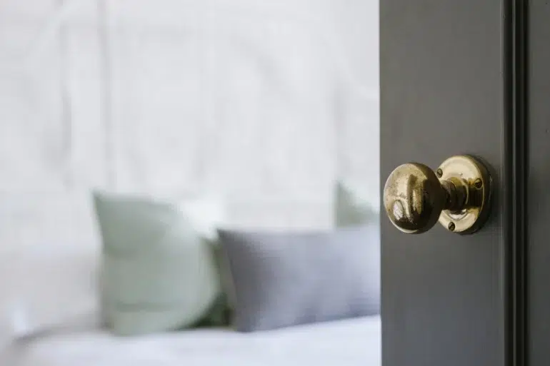 A close-up of a classic brass door knob on a dark wooden door, highlighting the elegance and timeless appeal of wooden door handles in home interiors.