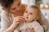 A parent gently brushing the teeth of a lip tie baby using a silicone finger brush to avoid discomfort.