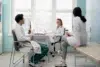 Three medical professionals in white coats have a relaxed discussion in a bright office. They appear engaged, conveying a collaborative atmosphere.