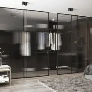 Modern bedroom with a sleek design, featuring glass-door wardrobes, wood panel walls, a gray bed, plush rug, decorative art, and serene lighting.