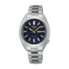 A silver metal Seiko watch with a blue dial, gold hour markers, and hands, displaying the day and date. The tone is elegant and sophisticated.