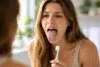 Person looking in mirror at white tongue even after brushing teeth