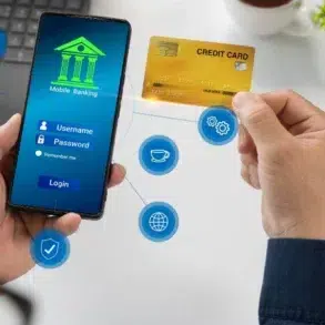 Person using mobile banking app on smartphone while holding a credit card, with digital finance icons floating nearby.