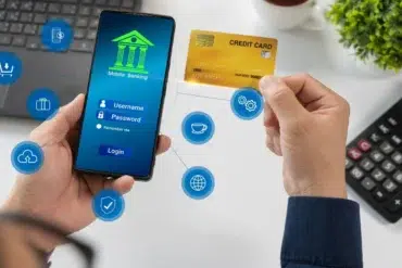 Person using mobile banking app on smartphone while holding a credit card, with digital finance icons floating nearby.