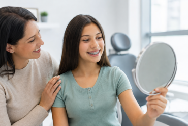 Teen smiling during orthodontic consultation with parent learning about Braces for Teens