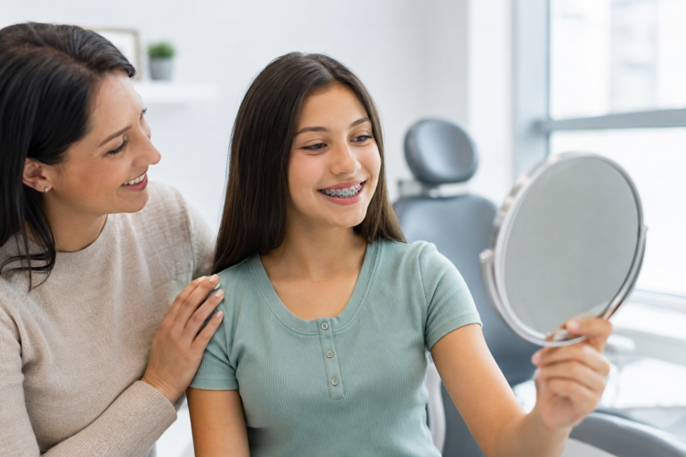 Teen smiling during orthodontic consultation with parent learning about Braces for Teens
