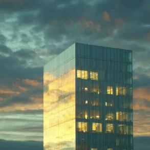A modern glass skyscraper reflects a dramatic sunset with golden and orange hues against a cloudy sky, creating a serene and majestic atmosphere.