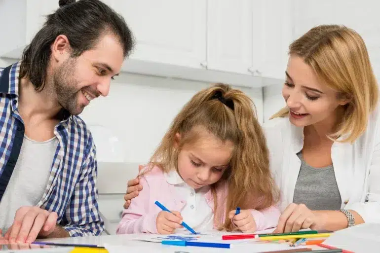 Singleton preschool learning moment with parents helping a young child draw and practice creativity at home