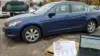 A blue sedan parked in a lot with laptops displaying a VIN and vehicle history report. Overcast sky and autumn trees set a somber, investigative tone.