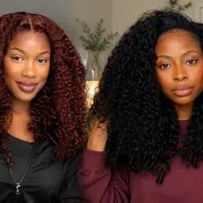 Two women with voluminous curly hair, one with dark red curls and the other with black curls, indoors with a neutral background.