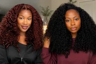 Two women with voluminous curly hair, one with dark red curls and the other with black curls, indoors with a neutral background.