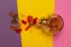 A glass jar spills colorful gummy bears onto a purple and yellow background, creating a playful and vibrant scene with assorted red, orange, and green candies.