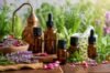 An arrangement of amber glass dropper bottles surrounded by fresh lavender, rose petals, and chamomile flowers, showcasing products from essential oil suppliers.