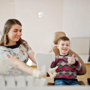 A young boy gives a thumbs up while sitting in a dental chair, showing how family dentistry blends aesthetic results with a positive patient experience for all ages.