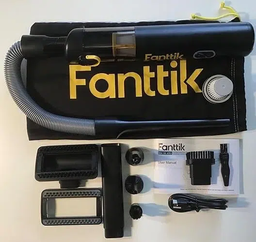 Compact black Fanttik cordless vacuum set on branded mat. Includes hose, nozzles, attachments, power cord, and user manual, conveying a sleek design.