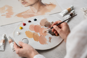 Artist mixing realistic skin color paint shades on a palette for portrait and craft artwork