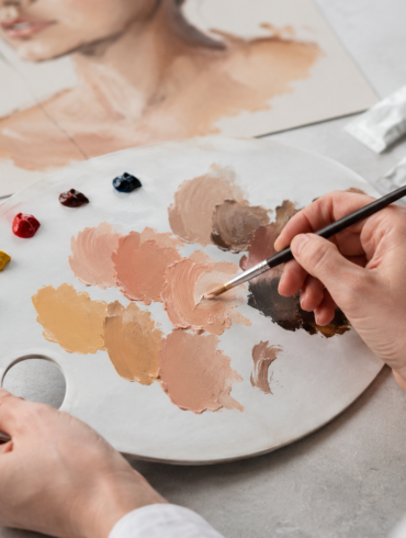 Artist mixing realistic skin color paint shades on a palette for portrait and craft artwork