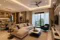 Modern living room with a beige sectional sofa, blue armchair, and marble coffee table. Sliding glass doors open to a balcony with greenery.