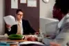 A Las Vegas Workers Comp Lawyer in a professional office setting, wearing glasses and a suit, reviewing legal documents during a consultation with a client.