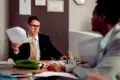 A Las Vegas Workers Comp Lawyer in a professional office setting, wearing glasses and a suit, reviewing legal documents during a consultation with a client.