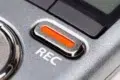 Close-up of a silver recording device with a prominent red REC button, symbolizing activation. The metallic texture adds a sleek, professional feel.
