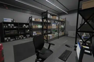 A tidy, well-lit storage room featuring shelves filled with organized boxes and folders. A desk with a computer, keyboard, and chair sits in the foreground.