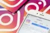 Close-up of a smartphone displaying Instagram's profile page, surrounded by cards featuring the Instagram logo on a gradient background. Social media theme.