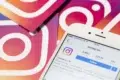 Close-up of a smartphone displaying Instagram's profile page, surrounded by cards featuring the Instagram logo on a gradient background. Social media theme.