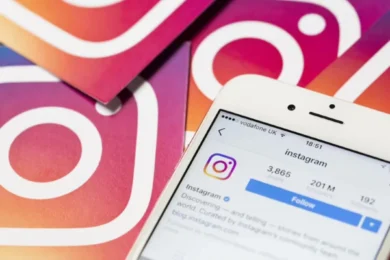Close-up of a smartphone displaying Instagram's profile page, surrounded by cards featuring the Instagram logo on a gradient background. Social media theme.