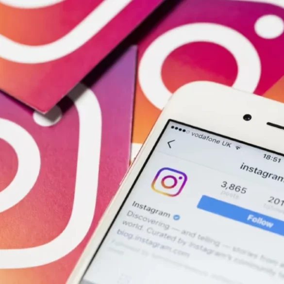 Close-up of a smartphone displaying Instagram's profile page, surrounded by cards featuring the Instagram logo on a gradient background. Social media theme.
