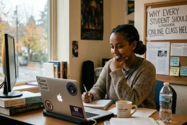 A woman sits at a desk smiling while looking at her laptop. Books, a mug, and a water bottle are nearby. A sign reads "Why Every Student Should Consider Online Class Help."
